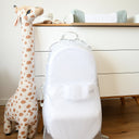 White baby bouncer with a lion head, tall giraffe toy, and wooden dresser in a nursery.