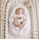 Baby in a white crib with a teddy bear
