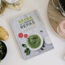Cookbook titled 'Mes Premiers Repas' on a table with ingredients and kitchen tools.