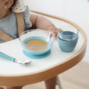Child sitting at a table with blue bowls and a spoon