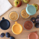 Fruit puree in small containers with fresh fruits on a wooden surface