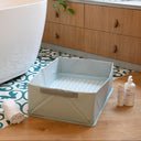 Bathroom with a white bathtub, wooden cabinet, and a gray pet crate on a patterned rug.