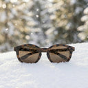 Sunglasses on a snowy surface with a blurred snowy landscape in the background