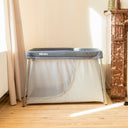 Portable crib in a room with a wooden floor and a decorative fireplace.