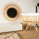 Wicker crib with decorative mirror and vase in a room setting