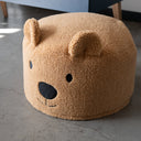 Brown bear-shaped ottoman on a concrete floor