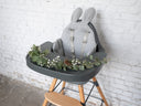 Gray high chair with bunny ears against a white brick wall