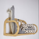 Rattan shelf with baby items including a plush toy and a pillow on a white background